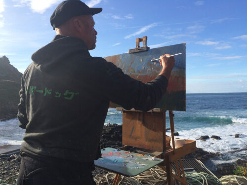 el artista Neil Pinkett pintando en plein air en Cape Cornwall sobre los acantilados