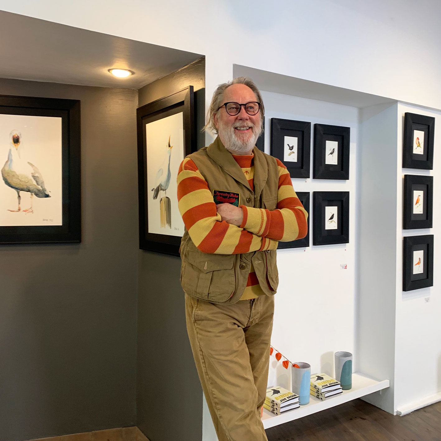 a photograph of the artist Jim Moir, otherwise known as the comedian Vic Reeves, with his paintings at Cornwall Contemporary gallery